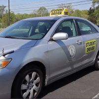 image of a silver car in a parking lot on a sunny day. 